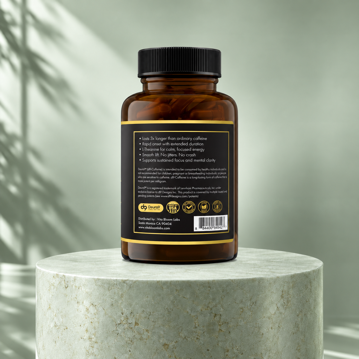 Caffeine 2.0 + L-Theanine side A bottle showing benefits, warnings, Deura9 information, and barcode on a sage green stone pedestal.