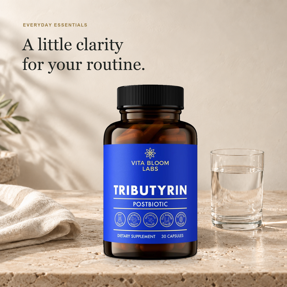 Tributyrin bottle beside a glass of water and linen in natural daylight, under the heading A little clarity for your routine.